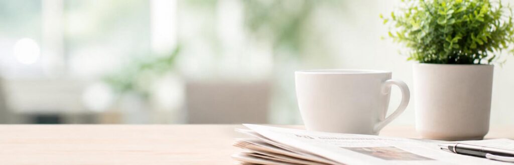 newspaper on a desk with a cup of coffee in a well lit area